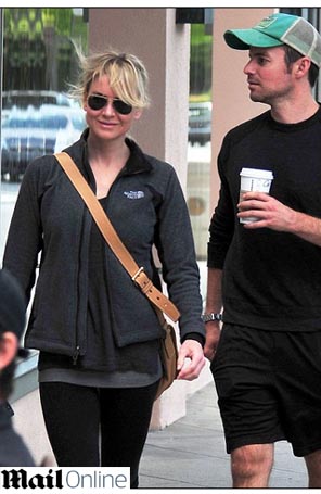 Renée Zellweger caminha sorridente com amigo
