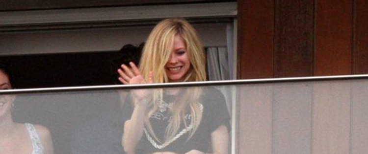 Avril Lavigne acena para fãs na sacada de hotel