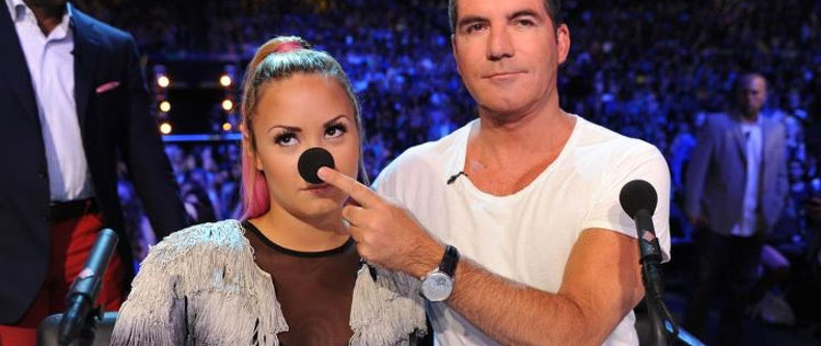 Demi Lovato cospe chiclete na mão de Simon Cowell durante gravações de <i>X Factor</i>