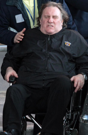 Fora do peso, Gerard Depardieu é visto em cadeiras de roda no aeroporto em Roma