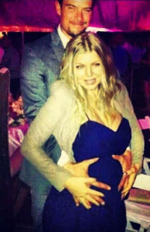 Josh Duhamel posa ao lado de Fergie com as mãos em sua barriga