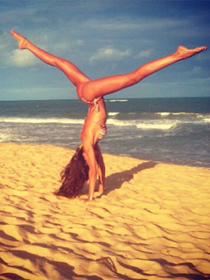 Izabel Goulart posa de ponta cabeça na praia e exibe a boa forma