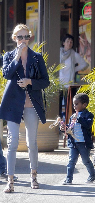 Com brinquedos na mão, filho de Charlize Theron passeia com a mãe