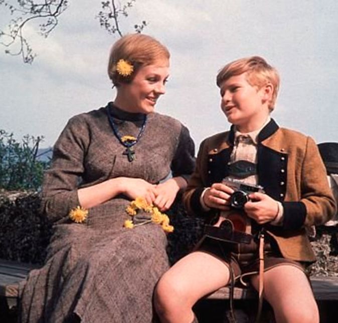 E mesmo com esse climão, a verdadeira Maria von Trapp aparece no filme, atrás de Julie Andrews, na cena em que a personagem passa sob uma arcada de tijolos na cidade cantando I Have Confidence. Mas calma, não precisa nem enxergar a senhora, já que é uma daquelas aparições que só a própria pessoa e a família dela conseguem notar. Nessa cena, Julie ainda chegou a tropeçar quando chega correndo no pátio da mansão Von Trapp. O momento não foi um acidente, mas o diretor Robert Wise decidiu manter na versão final, porque achou que combinava com o nervosismo da personagem. E mesmo com esse climão, a verdadeira Maria von Trapp aparece no filme, atrás de Julie Andrews, na cena em que a personagem passa sob uma arcada de tijolos na cidade cantando I Have Confidence. Mas calma, não precisa nem enxergar a senhora, já que é uma daquelas aparições que só a própria pessoa e a família dela conseguem notar. Nessa cena, Julie ainda chegou a tropeçar quando chega correndo no pátio da mansão Von Trapp. O momento não foi um acidente, mas o diretor Robert Wise decidiu manter na versão final, porque achou que combinava com o nervosismo da personagem.