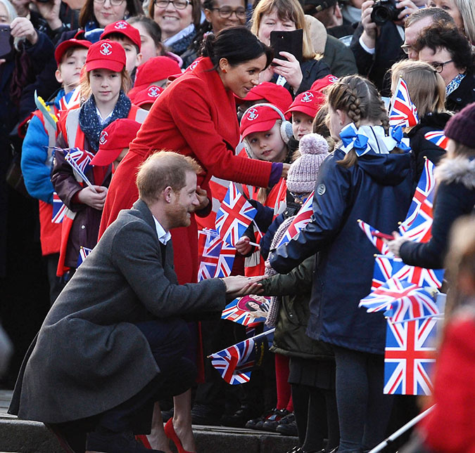 Meghan Markle e príncipe Harry se abaixam para deixar que crianças cegas toquem seus rostos