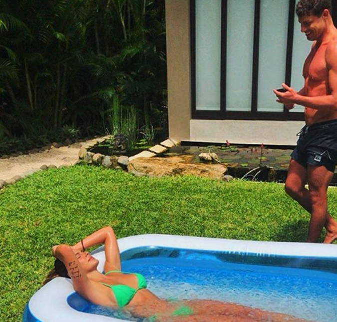 Mariana Goldfarb aproveita para tomar sol em uma piscininha de plástico ao lado de Cauã Reymond