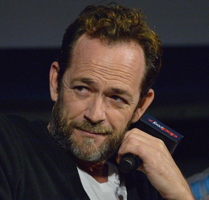 Nascido em 11 de outubro de 1966, Luke Perry morreu no dia 4 de março de 2019, aos 52 anos de idade, pegando todo mundo de surpresa. O ator, conhecido por seu papel em Barrados no Baile, sofreu um AVC (Acidente Vascular Cerebral) inesperado no final de fevereiro, e ficou internado na UTI de um hospital em Los Angeles, nos Estados Unidos, até o dia de sua morte. Na época, Luke estava no elenco fixo da famosa série Riverdale, onde interpretava Fred Andrews, pai de um dos personagens principais, Archie Andrews, vivido por KJ Apa. A trama teen, então, resolveu prestar uma linda homenagem ao artista. Com um episódio chamado In Memoriam (Em Memória, em português), descobrimos que Fred, personagem de Perry, é morto em um acidente de carro. Acontece que ele se sacrificou para salvar a vida de uma mulher, que na série foi interpretada por Shannen Doherty, grande amiga do ator e colega de elenco em Barrados no Baile. Além disso, o filho de Fred, Archie, reúne todos os seus amigos para trazer o corpo do pai de volta à Riverdale de forma única, o que fez com que o público se emocionasse bastante ao decorrer de todo o episódio. Muito significativo, não é?