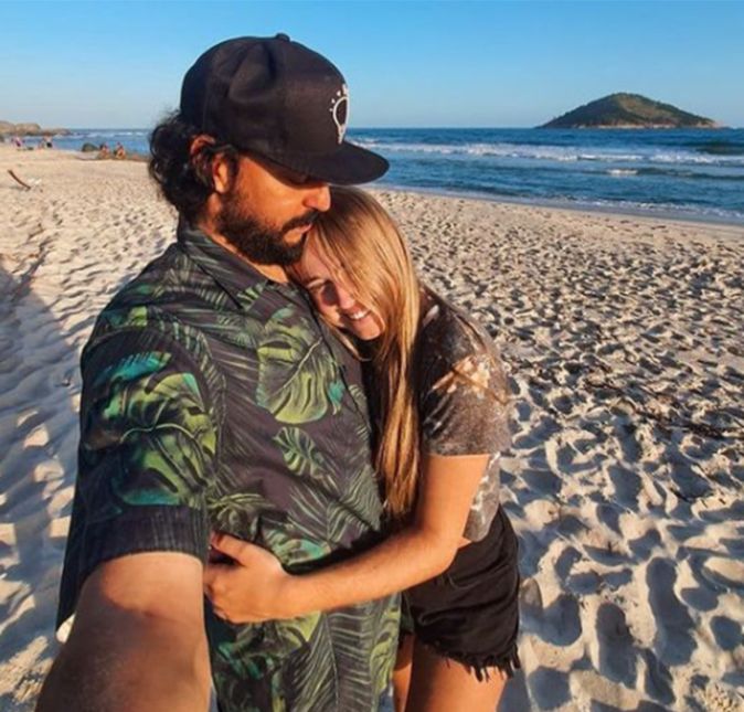 Gabriel O Pensador assumiu um romance com Gabriela Vicente, mulher 27 anos mais jovem, ao publicar essa foto. Na legenda, ele escreveu: A paisagem era a pintura e a retina era a tela. Era só subir a cortina da pálpebra. E a menina foi embora e carregou dentro dela. Tanto mar que transbordou sua memória. Delicada a cada passo agora tenta evitar. Mas ainda vai deixando pegadas. Salgadas, molhadas, cheias de areia áspera. E ao mesmo tempo doce e macia. A gaivota que voava e a sua sombra na encosta. Cada gota que mudava os tons de cinza das rochas. As palavras que escutava e tudo mais que ela gosta. Tudo isso em seu sorriso cabia. E a beleza dos lugares e pessoas que viu. E o silêncio disfarçado atrás do som que se ouvia. E o calor de cada abraço quando o vento era nosso. Ela trouxe sem saber que trazia. Quando eu vejo nos seus olhos o retrato mais puro. Da beleza que eu procuro na vida. Sinto a vertigem de um cego e danço em círculos. E sigo adivinhando a cor do amor a cada dia.