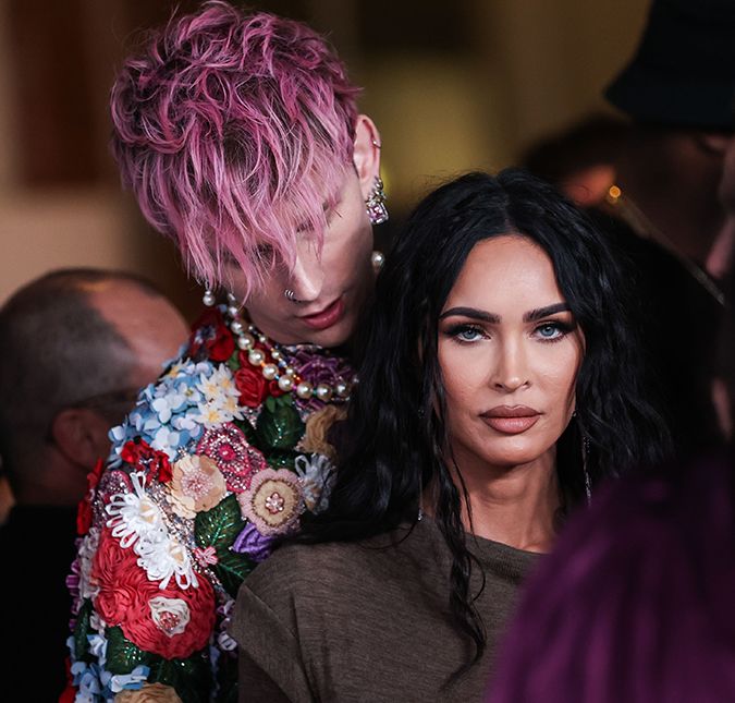 Falando em noivado, a atriz foi pedida em casamento com um anel poderoso que continha duas pedronas alusivas ao nascimento de ambos: uma de diamante que representa Machine e a outra de esmeralda que representa Megan. O valor? 65 mil euros, cerca de 413 mil reais. Mas não foi isso que chamou a atenção dos internautas - e sim os espinhos. Oi? Durante entrevista à Vogue, o cantor contou que pensou em todos os detalhes ao escolher o design único da joia. Criado em parceria com o joalheiro Stephen Webster, o anel foi feito sob medida e machuca o dedo da amada se ela tentar tirá-lo.  É uma esmeralda colombiana pura, sem tratamento. Foi apenas esculpida em formato de lágrima, direto da mina. E o diamante era diretamente de Stephen. O conceito é que o anel pode se separar para fazer dois anéis. Quando estão juntos, são mantidos no lugar por um ímã. Você vê como se encaixa? E então forma um coração obscuro. E você vê isso aqui? As bandas são realmente espinhos. Então, se ela tentar tirar, dói. Amor é dor!.