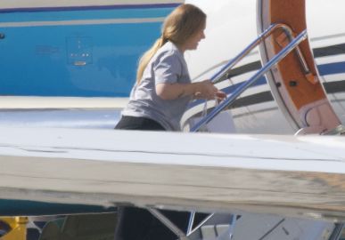 Adele aparece entrando em jatinho usando moletom e sem maquiagem