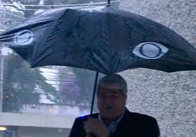 Datena fica todo molhado após guarda-chuva quebrar ao vivo: - <i>Acho que vou ter que trocar de roupa</i>