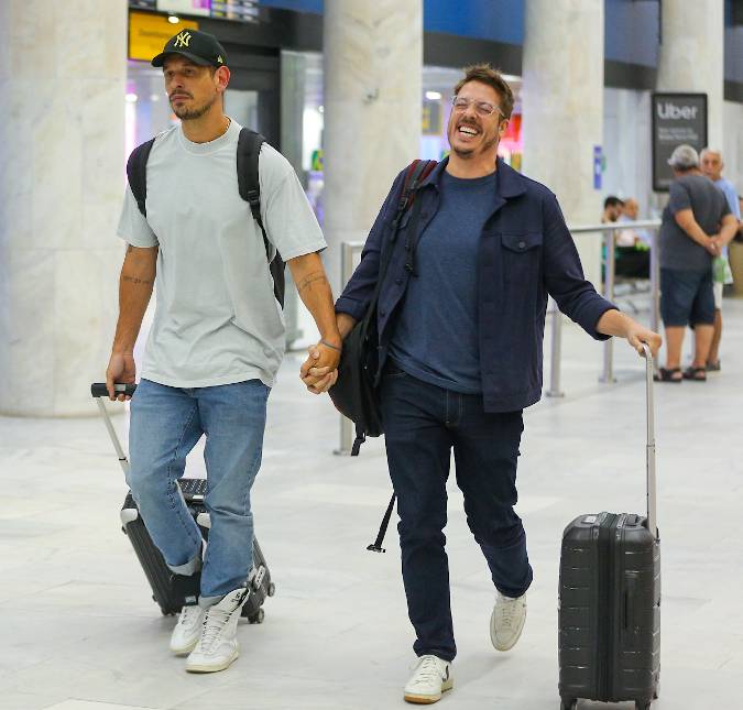 Amigos de longa data! João Vicente De Castro e Fábio Porchat andam de mãos dadas em aeroporto