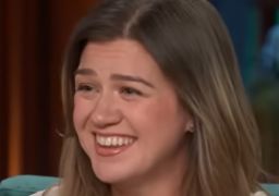 Kelly Clarkson se diverte com incidente no <i>look</i> durante <i>show</i>: <i>- Ops, olha só meus peitos</i>